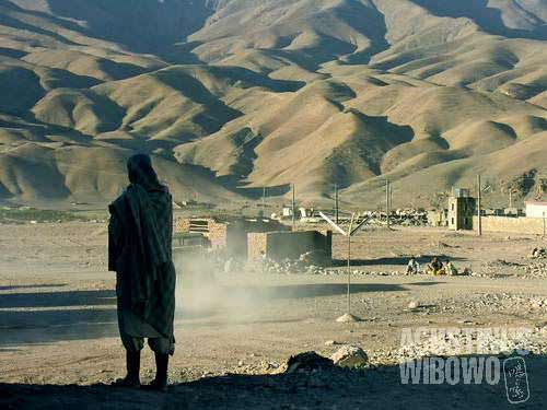 A man looking at the rugged mountains beyond the village of Chihst o Sharif.