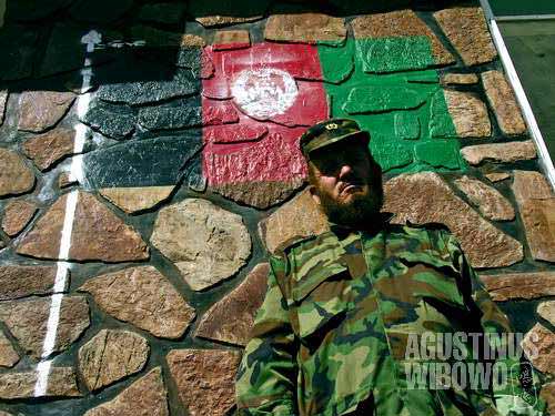 An Afghan military commander under the tricolor flag of Afghanistan painted on wall of soldier dormitory in Chekhcheran.