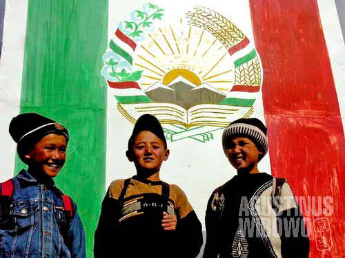 Boys of Murghab, in front of Tajik banner with the tricolor flag and coat-of-arms, of which important element is a snow mountain