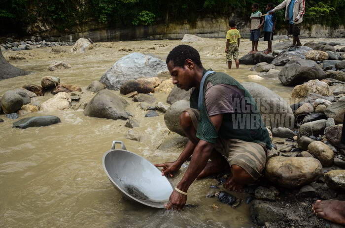 Penduduk lokal berusaha menambang emas yang mengalir di sungai dengan cara tradisional